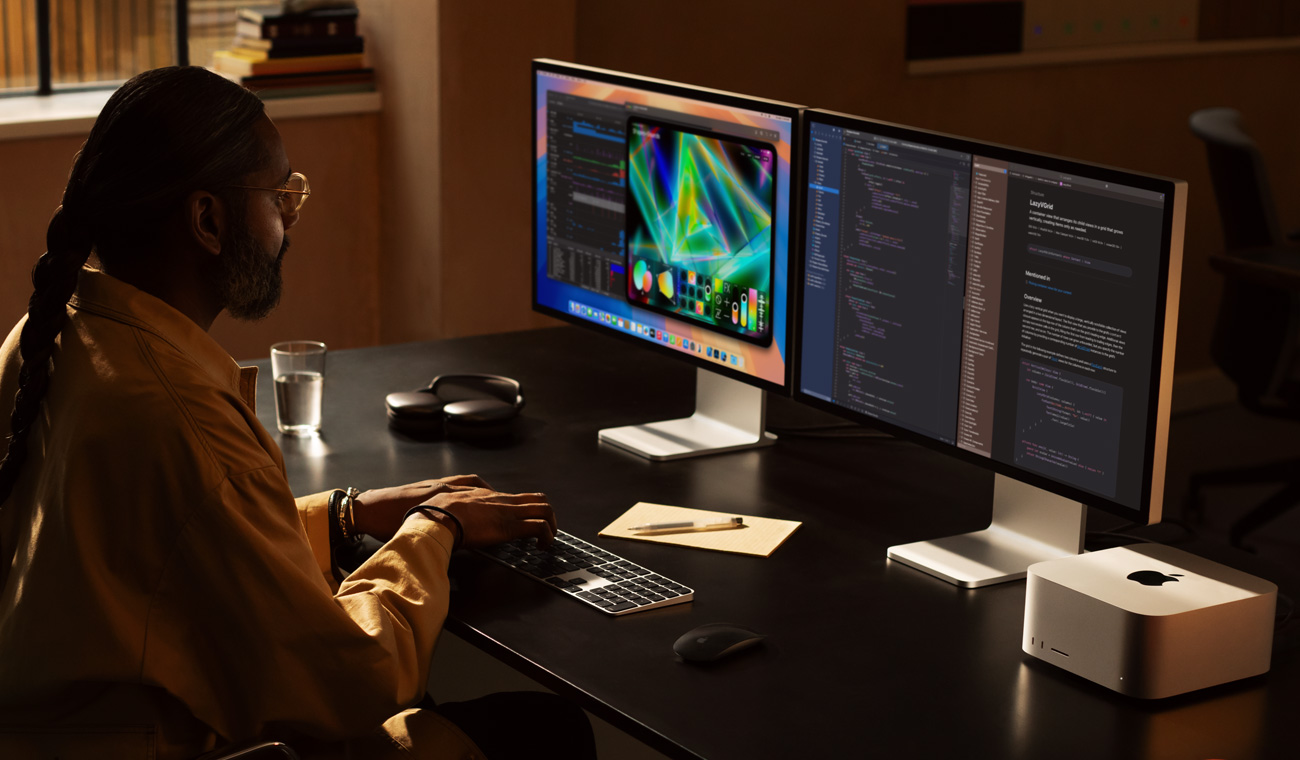 Profissional trabalhando no Mac Studio com dois monitores Studio Display.