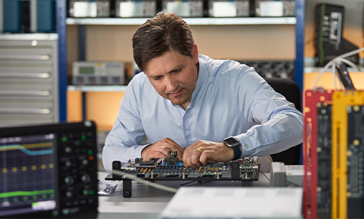 Greg arbeitet in einem Hardware Engineering Lab umgeben von Testinstrumenten für Chips.