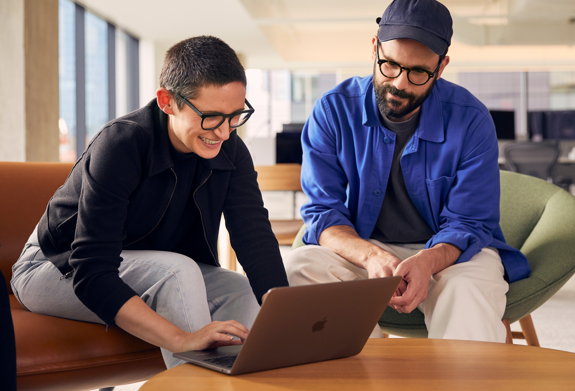 موظفان بشركة Apple يعملان معاً على جهاز MacBook.
