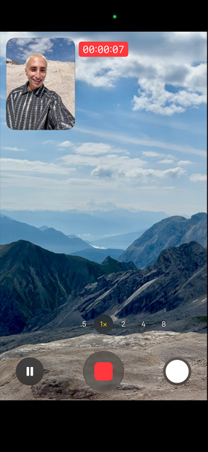 Una persona muestra un video con captura dual grabándose con la cámara frontal mientras graba un paisaje montañoso con la cámara trasera