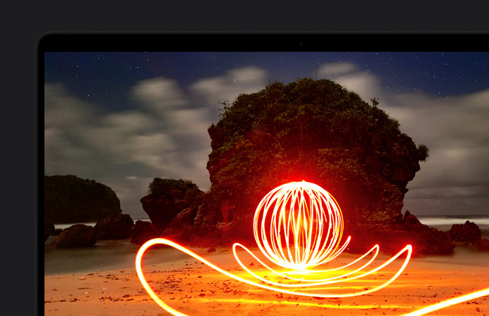 MacBook Pro-skærm med en stærkt lysende kunstinstallation på en strand, der demonstrerer skærmens imponerende kontrast takket være Extreme Dynamic Range